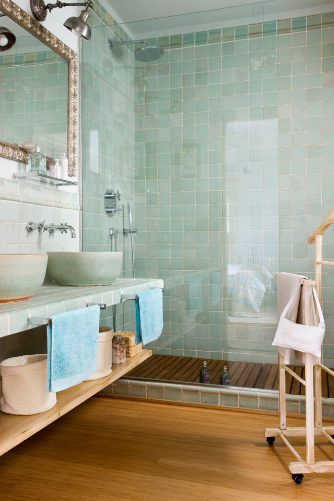 Inredning av ett medelhavsstil mellanstort grön grönt badrum med dusch, med öppna hyllor, gröna skåp, en hörndusch, grön kakel, keramikplattor, vita väggar, ett fristående handfat, kaklad bänkskiva och beiget golv