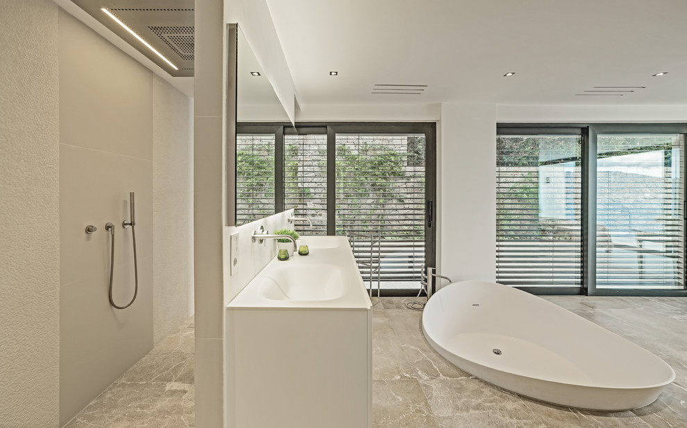 Modelo de cuarto de baño principal contemporáneo extra grande con armarios con paneles lisos, puertas de armario blancas, bañera exenta, ducha abierta, paredes blancas, lavabo integrado y ducha abierta