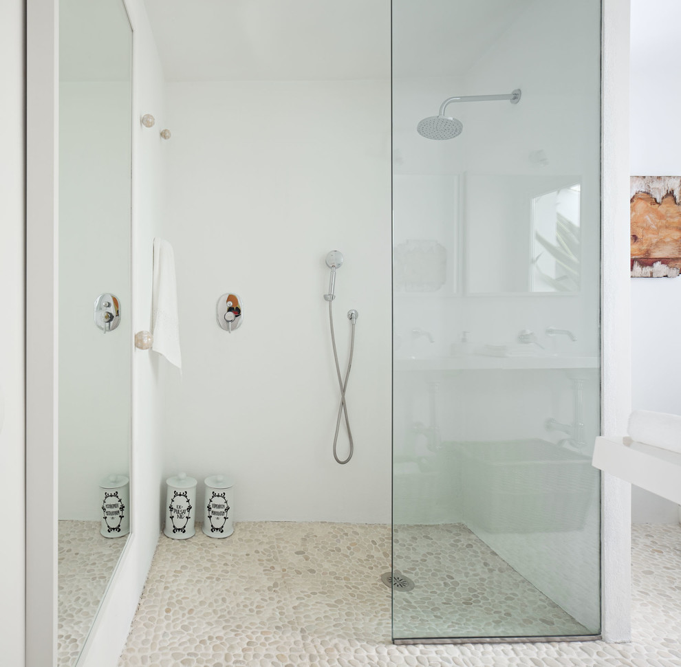 Modelo de cuarto de baño mediterráneo de tamaño medio con ducha a ras de suelo, lavabo suspendido, paredes blancas y aseo y ducha