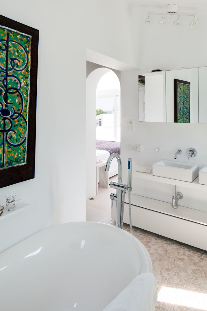 Ejemplo de cuarto de baño principal mediterráneo de tamaño medio con armarios abiertos, puertas de armario blancas, bañera exenta, combinación de ducha y bañera, paredes blancas y lavabo sobreencimera