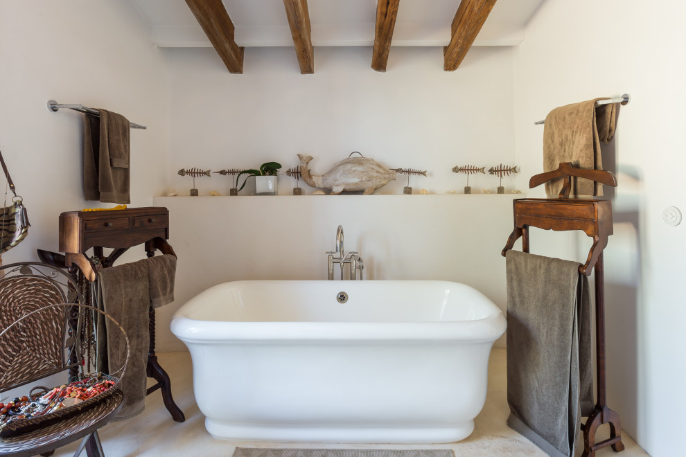 Diseño de cuarto de baño mediterráneo con bañera exenta, paredes blancas y suelo beige