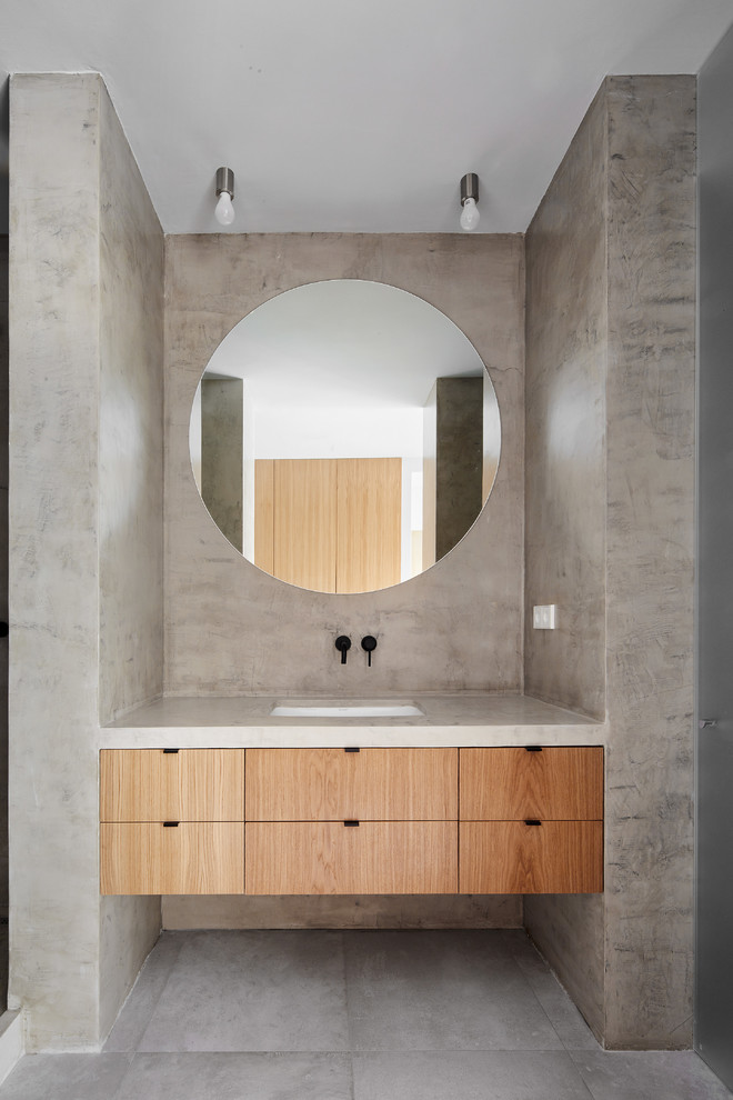 Réalisation d'une salle de bain design en bois brun avec un placard avec porte à panneau encastré, un mur gris, un lavabo intégré et un sol gris.