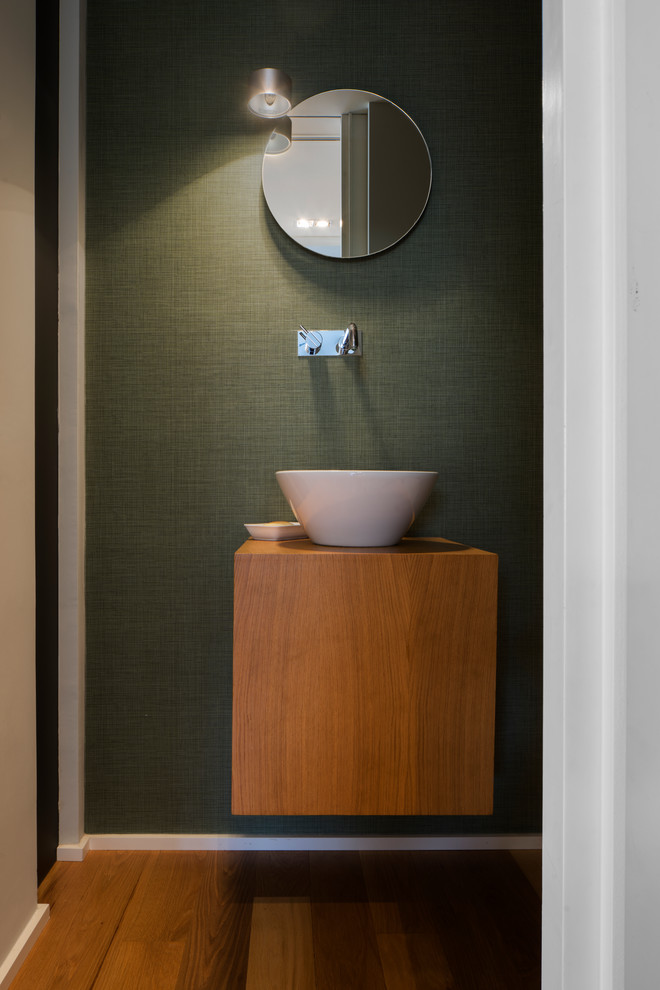 Imagen de cuarto de baño contemporáneo de tamaño medio con puertas de armario de madera oscura, paredes verdes, suelo de madera en tonos medios, aseo y ducha, lavabo sobreencimera y encimera de madera