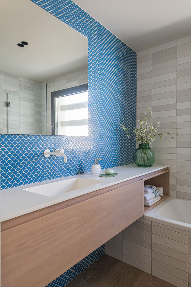 Inspiration for a medium sized mediterranean family bathroom in Other with light wood cabinets, an alcove bath, blue tiles, light hardwood flooring, white worktops, a single sink, flat-panel cabinets, mosaic tiles, an integrated sink, beige floors and a floating vanity unit.