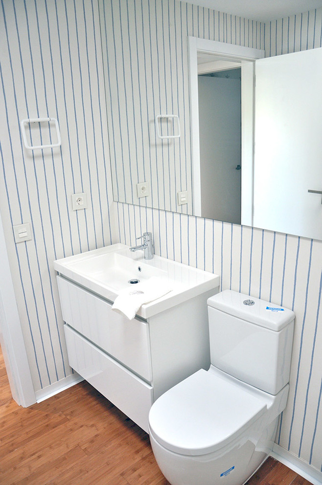 Imagen de cuarto de baño principal moderno pequeño con armarios con paneles lisos, puertas de armario blancas, sanitario de una pieza, lavabo suspendido, encimera de acrílico y ducha con puerta corredera
