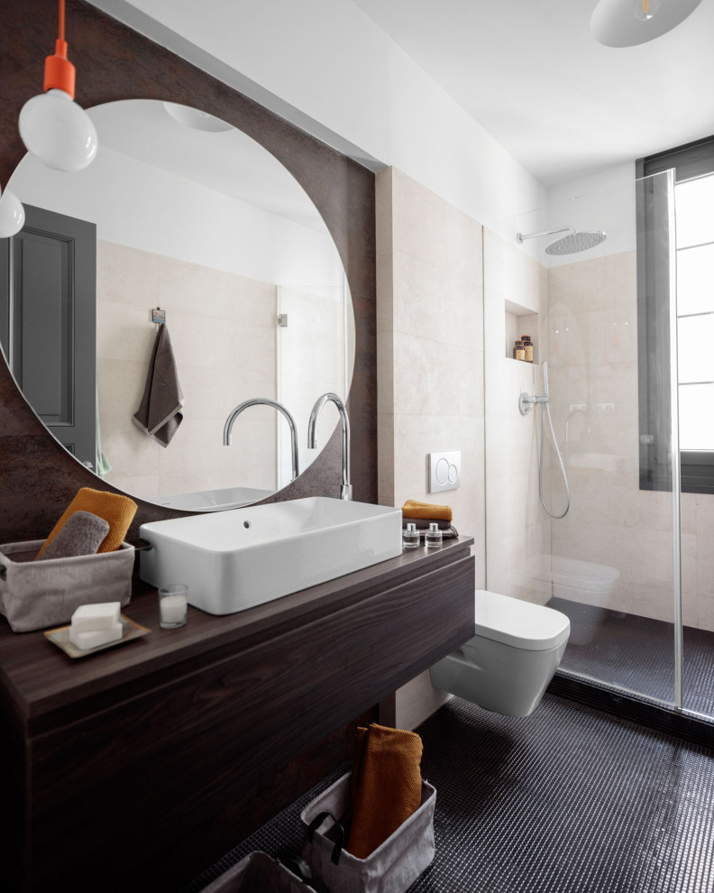 Inspiration för ett mellanstort funkis brun brunt badrum med dusch, med släta luckor, skåp i mörkt trä, en dusch i en alkov, en vägghängd toalettstol, beige kakel, porslinskakel, vita väggar, ett fristående handfat, träbänkskiva och grått golv
