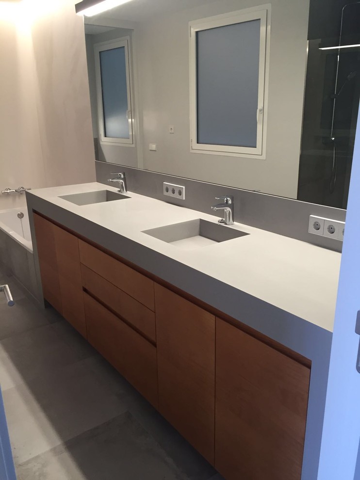 Foto di una grande stanza da bagno moderna con consolle stile comò, ante in legno chiaro, lavabo integrato e top in superficie solida