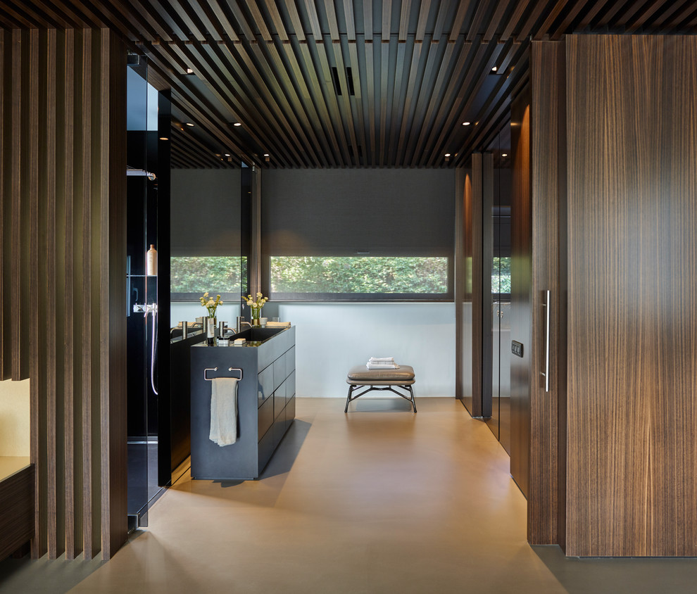 Immagine di una stanza da bagno contemporanea con ante lisce, ante nere, lavabo integrato e pavimento grigio