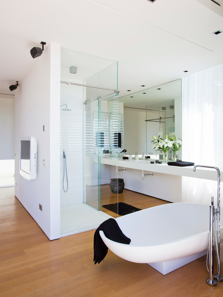 На фото: большая главная ванная комната в современном стиле с открытыми фасадами, отдельно стоящей ванной, угловым душем, белыми стенами, паркетным полом среднего тона, монолитной раковиной, столешницей из искусственного кварца и душем с раздвижными дверями с