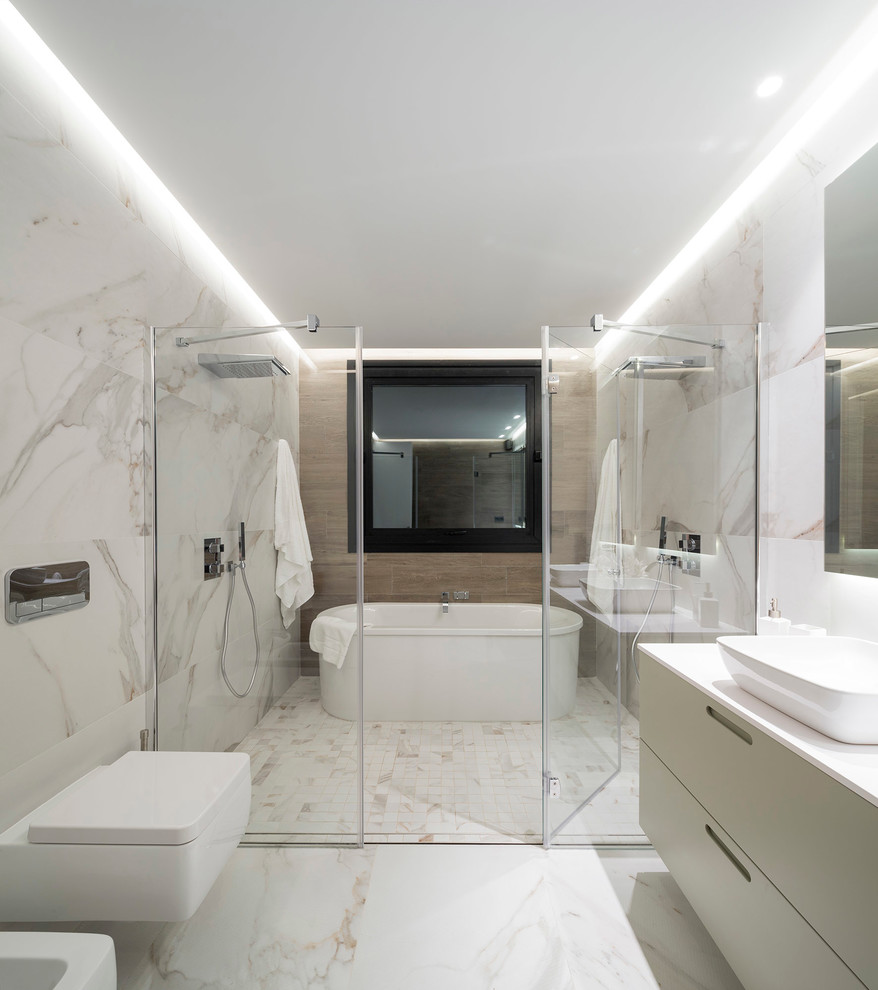 Foto de cuarto de baño contemporáneo con bañera exenta, ducha doble, sanitario de pared, paredes blancas y lavabo sobreencimera