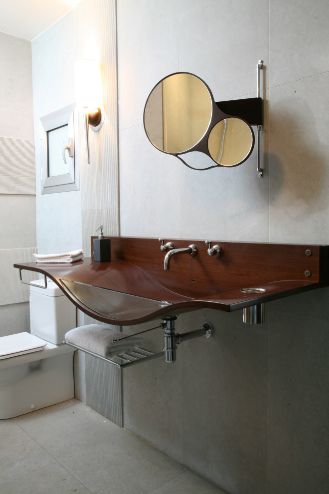 Modelo de cuarto de baño único contemporáneo de tamaño medio con sanitario de una pieza, baldosas y/o azulejos grises, baldosas y/o azulejos de porcelana, suelo de baldosas de porcelana, aseo y ducha, lavabo integrado, encimera de madera, suelo gris y encimeras marrones