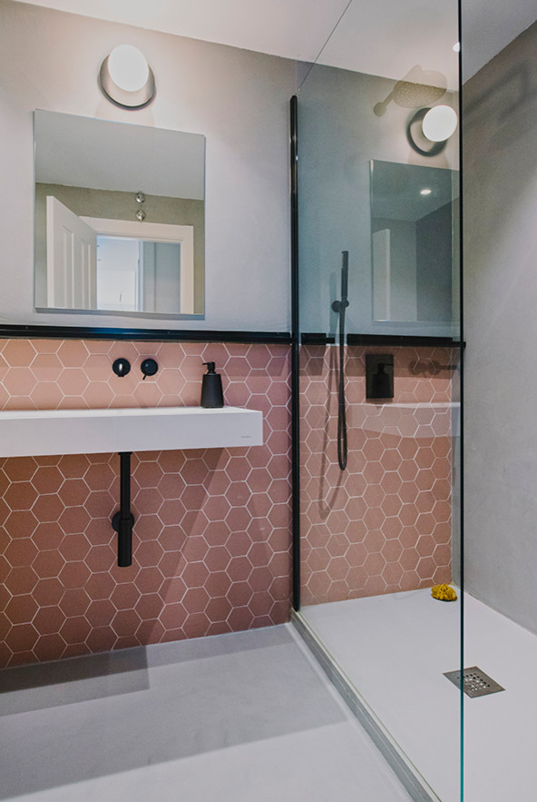 Стильный дизайн: маленькая ванная комната в современном стиле с белыми фасадами, душевой комнатой, инсталляцией, розовой плиткой, керамогранитной плиткой, серыми стенами, полом из керамогранита, душевой кабиной, раковиной с несколькими смесителями, столешницей из искусственного камня, серым полом, душем с распашными дверями и белой столешницей для на участке и в саду - последний тренд