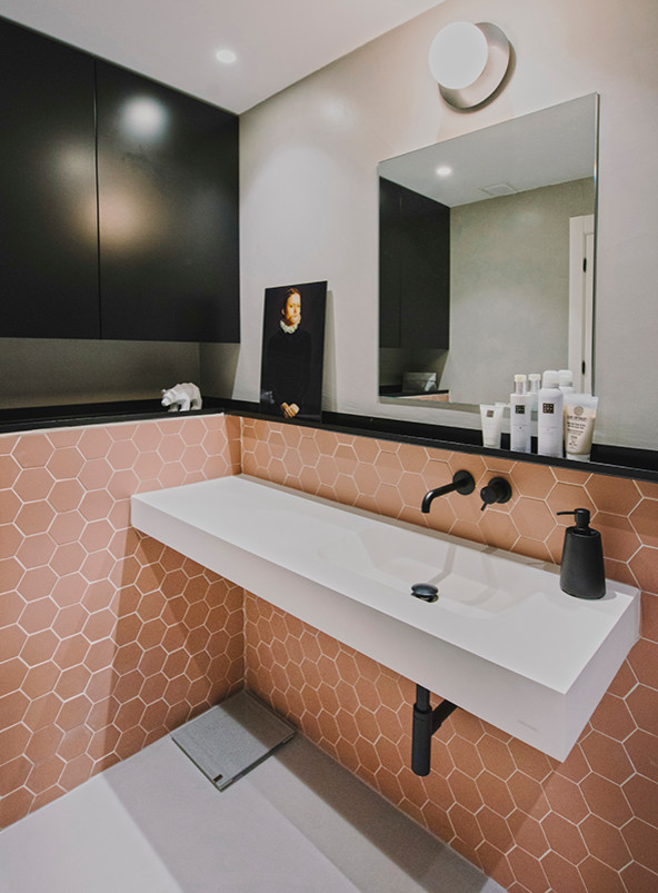 Foto på ett litet funkis vit badrum med dusch, med vita skåp, våtrum, en vägghängd toalettstol, rosa kakel, porslinskakel, grå väggar, klinkergolv i porslin, ett avlångt handfat, bänkskiva i akrylsten, grått golv och dusch med gångjärnsdörr