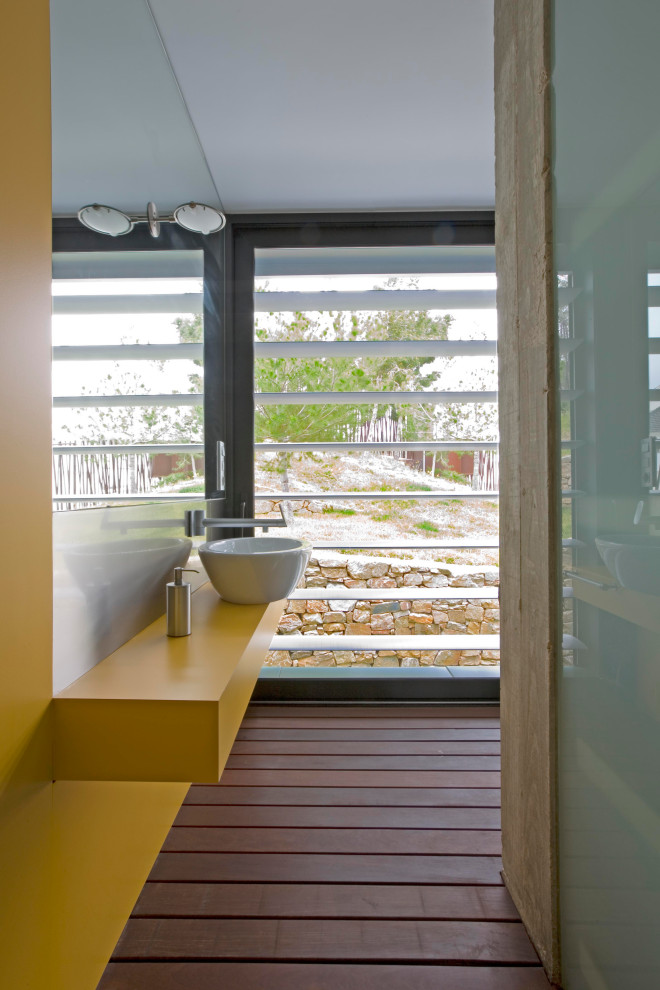 Стильный дизайн: ванная комната среднего размера в современном стиле с желтыми фасадами, желтыми стенами, душевой кабиной, настольной раковиной, коричневым полом, желтой столешницей, тумбой под одну раковину и подвесной тумбой - последний тренд