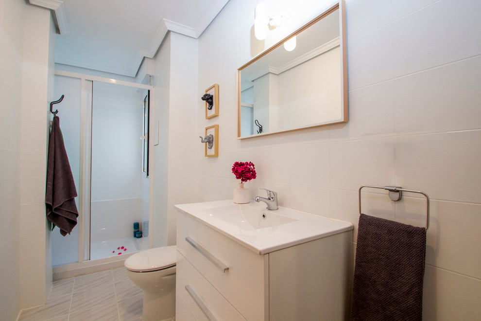 Ejemplo de cuarto de baño escandinavo de tamaño medio con armarios con paneles lisos, puertas de armario blancas, ducha empotrada, baldosas y/o azulejos blancos, baldosas y/o azulejos de cerámica, aseo y ducha y lavabo integrado