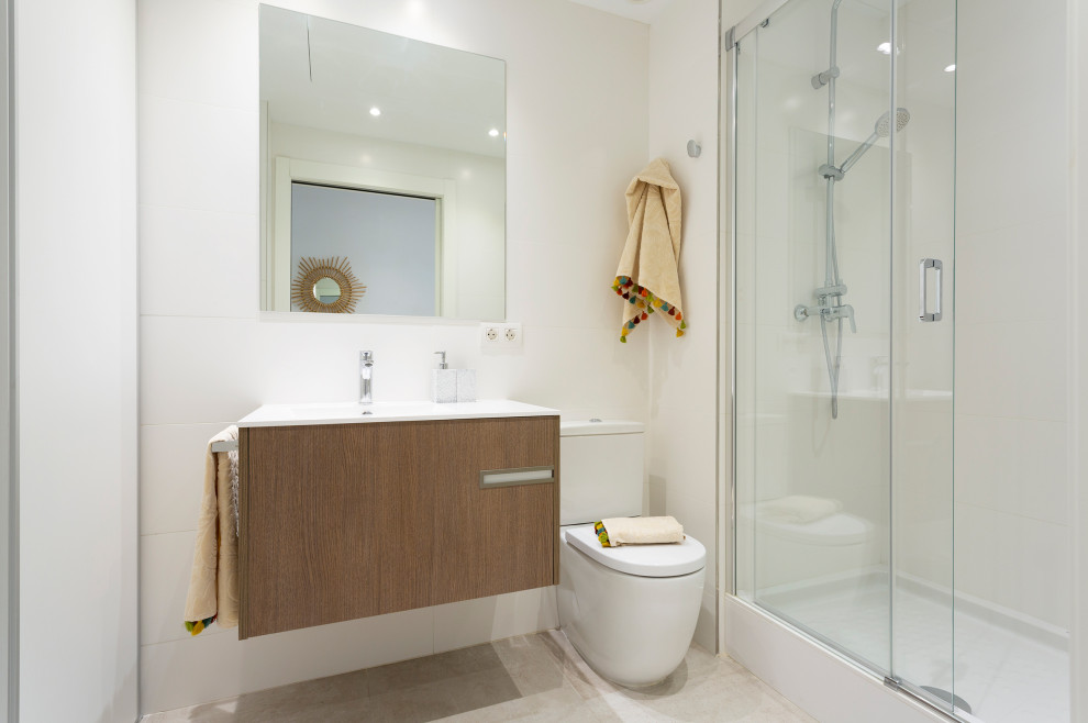 Exempel på ett mellanstort modernt vit vitt badrum med dusch, med släta luckor, skåp i mörkt trä, våtrum, ett urinoar, vit kakel, keramikplattor, vita väggar, klinkergolv i keramik, ett avlångt handfat, bänkskiva i akrylsten, beiget golv och dusch med skjutdörr