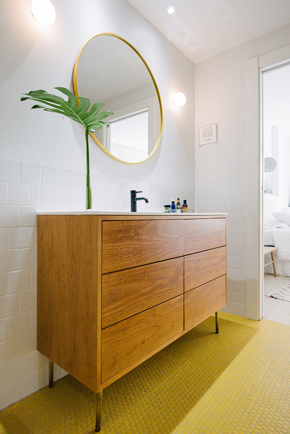 Пример оригинального дизайна: главная ванная комната в стиле модернизм с фасадами островного типа, белыми фасадами, отдельно стоящей ванной, душем в нише, инсталляцией, белой плиткой, белыми стенами, полом из мозаичной плитки, столешницей из искусственного камня, желтым полом, душем с раздвижными дверями и белой столешницей
