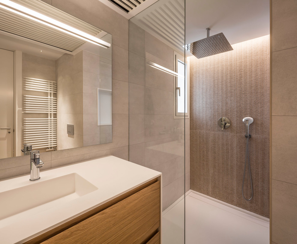 Photo of a large contemporary ensuite bathroom in Valencia with freestanding cabinets, black cabinets, an alcove bath, a one-piece toilet, grey tiles, ceramic tiles, grey walls, medium hardwood flooring, an integrated sink, engineered stone worktops, brown floors and white worktops.