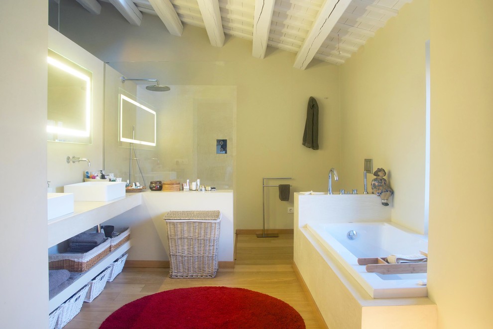 Idées déco pour une salle de bain principale méditerranéenne de taille moyenne avec une baignoire posée, une douche d'angle, un mur jaune, un sol en bois brun, une vasque et un plan de toilette en béton.