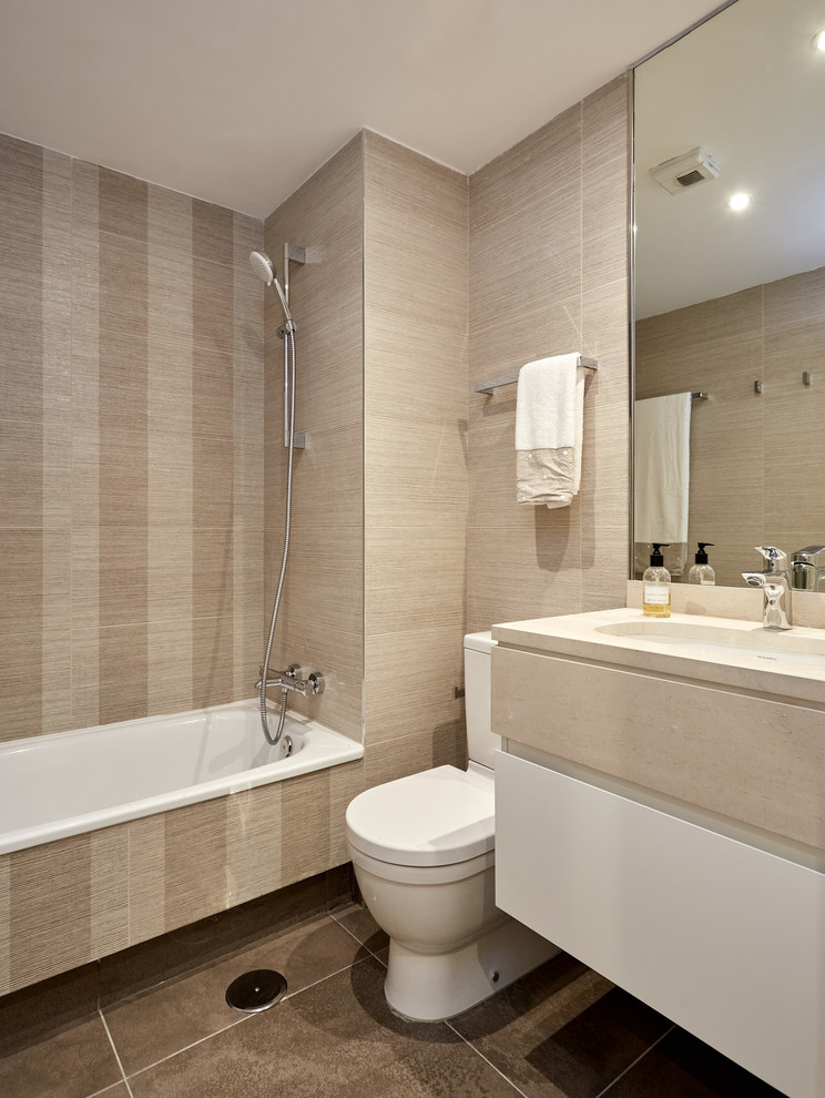 Medium sized classic ensuite bathroom in Madrid with freestanding cabinets, beige cabinets, a built-in bath, a wall mounted toilet, brown tiles, beige walls, a trough sink, marble worktops, brown floors and beige worktops.