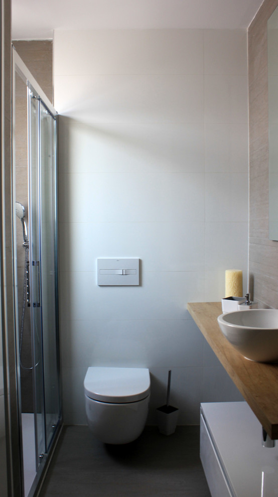 Foto de cuarto de baño clásico renovado de tamaño medio con armarios con paneles lisos, puertas de armario blancas, ducha empotrada, sanitario de pared, paredes blancas, aseo y ducha y lavabo sobreencimera