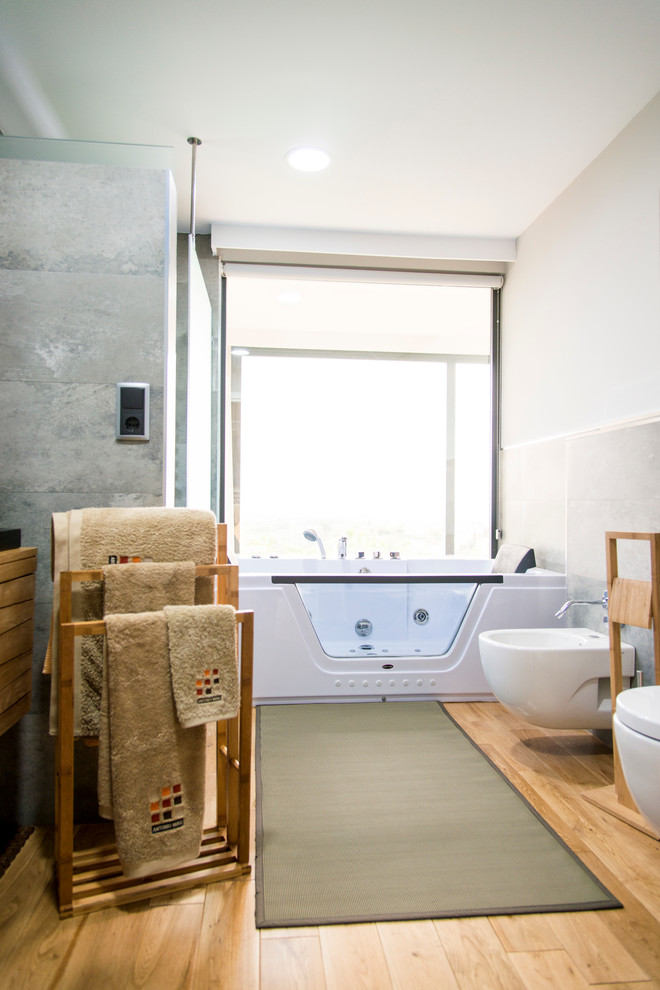 Foto de cuarto de baño principal actual grande con jacuzzi, combinación de ducha y bañera, bidé, paredes blancas, suelo de madera en tonos medios y lavabo encastrado
