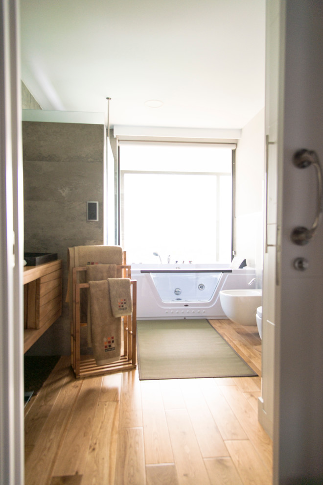 Ejemplo de cuarto de baño principal actual grande con jacuzzi, combinación de ducha y bañera, bidé, paredes beige, suelo de madera en tonos medios y lavabo encastrado