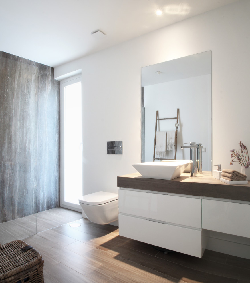 Mittelgroßes Modernes Duschbad mit flächenbündigen Schrankfronten, weißen Schränken, Wandtoilette, weißer Wandfarbe, Aufsatzwaschbecken, braunem Boden und brauner Waschtischplatte in Sonstige