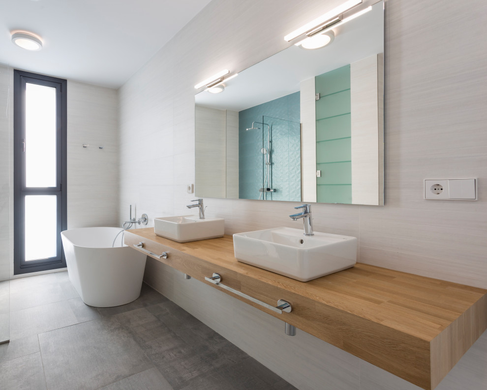 Foto de cuarto de baño flotante contemporáneo grande con puertas de armario blancas, baldosas y/o azulejos beige, encimera de madera y encimeras marrones