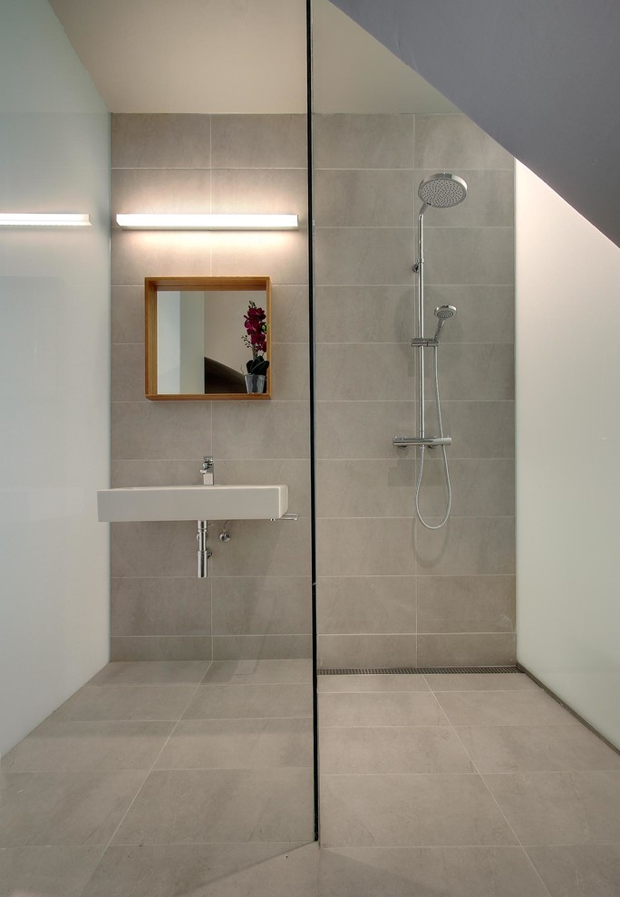 Modelo de cuarto de baño gris y blanco nórdico de tamaño medio con ducha a ras de suelo, paredes grises, suelo de baldosas de cerámica, aseo y ducha y lavabo suspendido