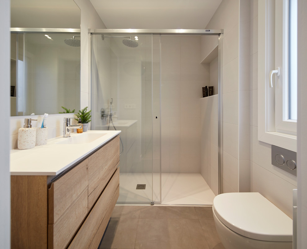 Exempel på ett litet nordiskt badrum med dusch, med släta luckor, skåp i mellenmörkt trä, en kantlös dusch, en vägghängd toalettstol, grå kakel, cementkakel, klinkergolv i keramik, ett undermonterad handfat, grått golv och dusch med skjutdörr
