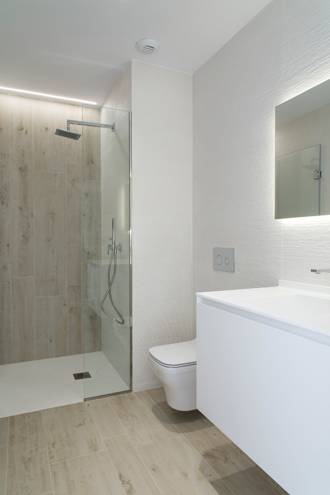 Inspiration for a small scandi shower room bathroom in Other with flat-panel cabinets, white cabinets, a built-in shower, a wall mounted toilet, white walls, an integrated sink and a hinged door.