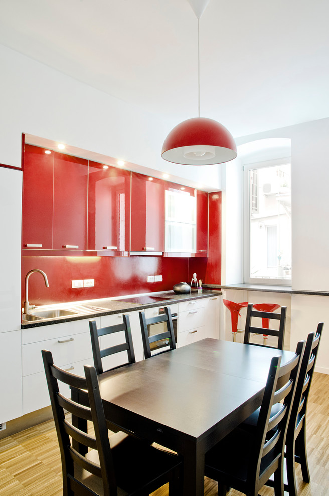 Пример оригинального дизайна: прямая кухня среднего размера в современном стиле с обеденным столом, накладной мойкой, плоскими фасадами, красными фасадами, красным фартуком, белой техникой и светлым паркетным полом