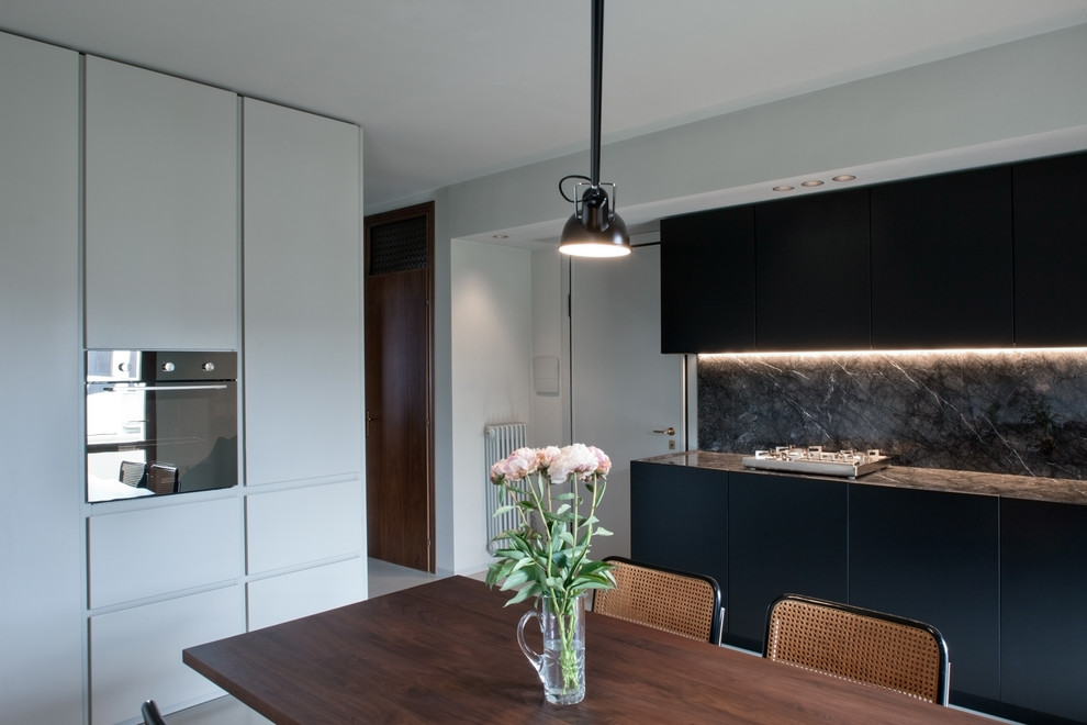 Idee per una cucina moderna di medie dimensioni con ante lisce, ante nere, elettrodomestici in acciaio inossidabile e nessuna isola