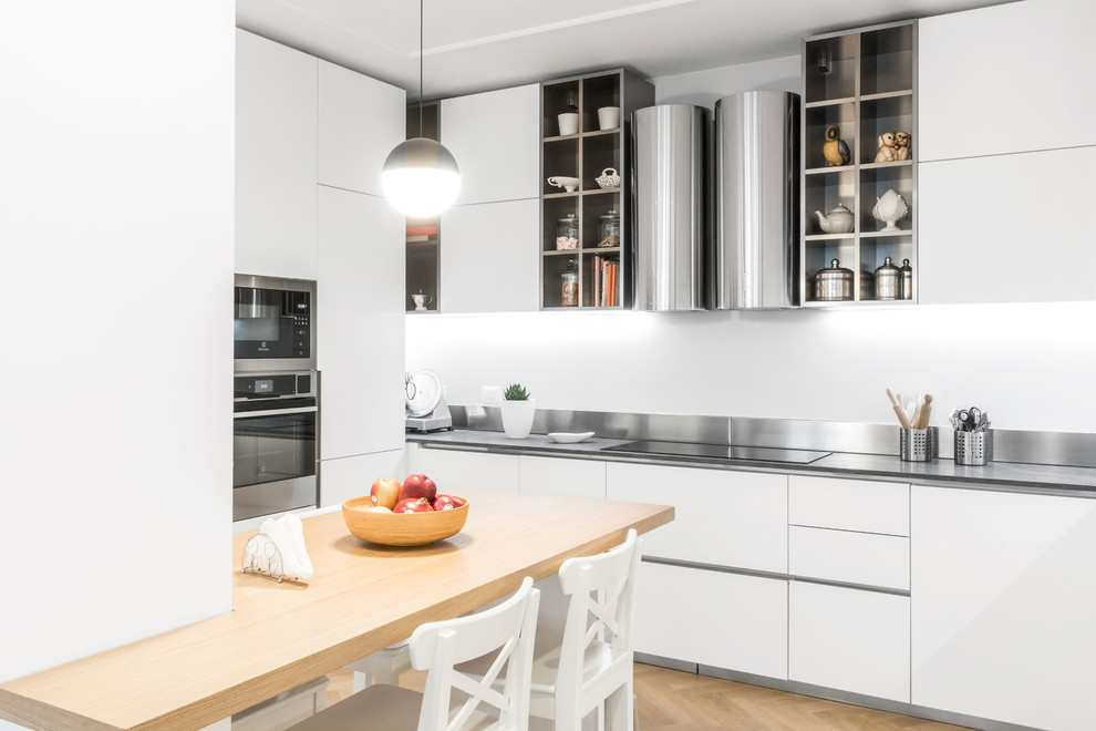 Contemporary kitchen in Milan with flat-panel cabinets, white cabinets, medium hardwood flooring, an island, brown floors and grey worktops.