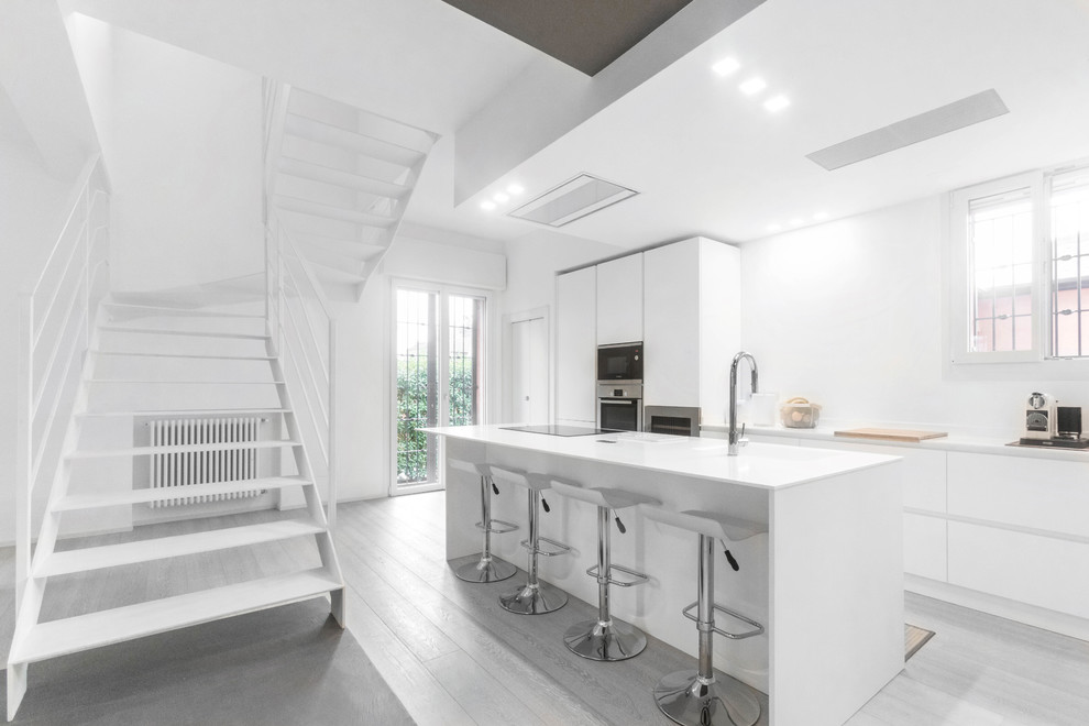 Esempio di una cucina minimal con ante lisce, ante bianche, elettrodomestici in acciaio inossidabile, pavimento grigio e top bianco