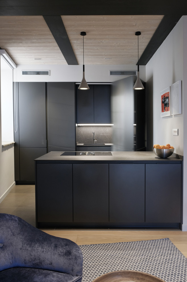 Modern inredning av ett mellanstort svart svart kök, med laminatbänkskiva, ljust trägolv, beiget golv, en undermonterad diskho, släta luckor, svarta skåp, grått stänkskydd, integrerade vitvaror och en halv köksö