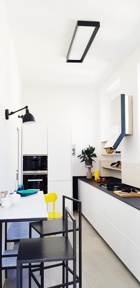 Idee per una piccola cucina contemporanea con ante lisce, ante bianche, elettrodomestici da incasso, penisola, pavimento grigio e top nero