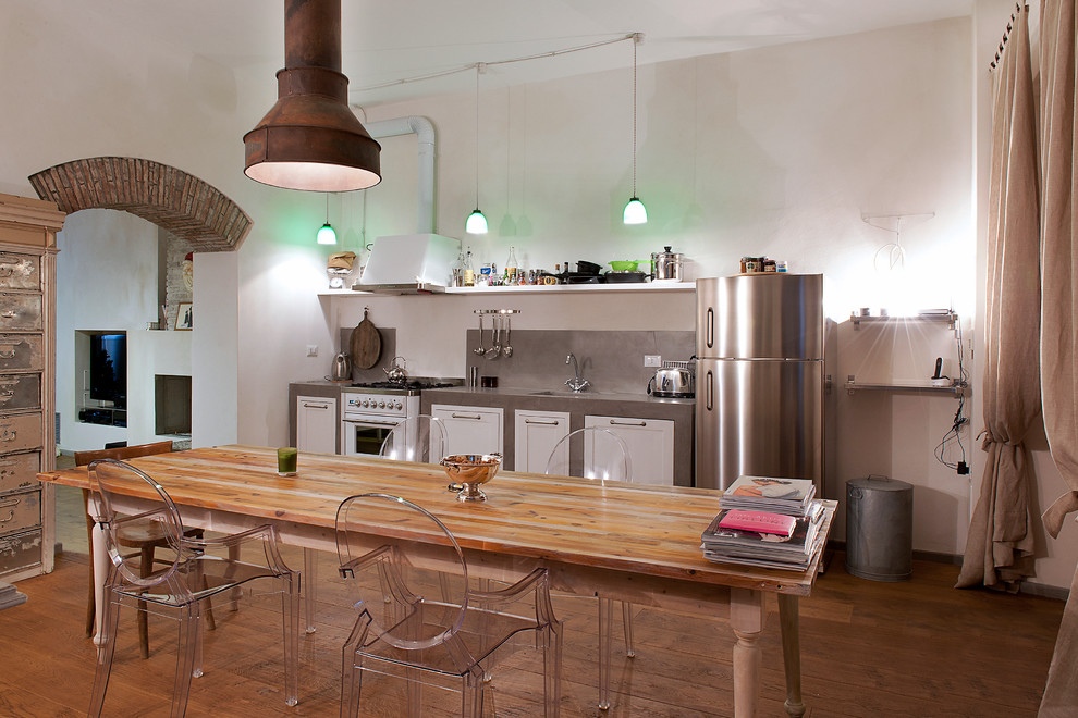 フィレンツェにあるインダストリアルスタイルのおしゃれなキッチン (シェーカースタイル扉のキャビネット、白いキャビネット、コンクリートカウンター、無垢フローリング、アイランドなし) の写真
