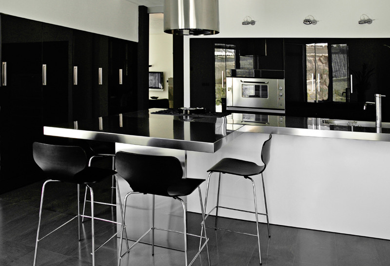 Immagine di una grande cucina design con lavello da incasso, ante lisce, ante nere, top in acciaio inossidabile, elettrodomestici in acciaio inossidabile, pavimento in marmo, pavimento nero, top grigio, soffitto ribassato e penisola