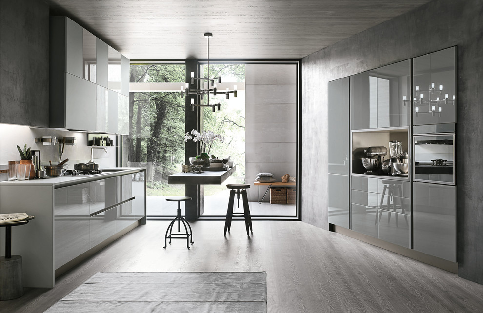 Cette image montre une cuisine parallèle design avec un placard à porte plane, des portes de placard grises, un sol en bois brun et îlot.