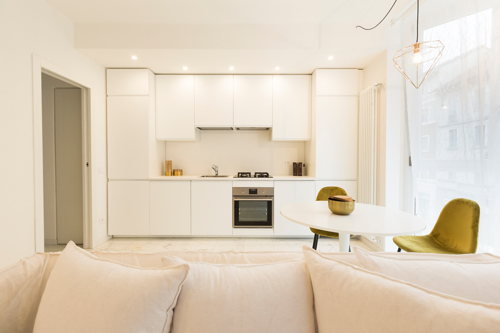 Idéer för att renovera ett mellanstort medelhavsstil vit linjärt vitt kök med öppen planlösning, med en nedsänkt diskho, släta luckor, vita skåp, rostfria vitvaror, marmorgolv, en halv köksö och vitt golv