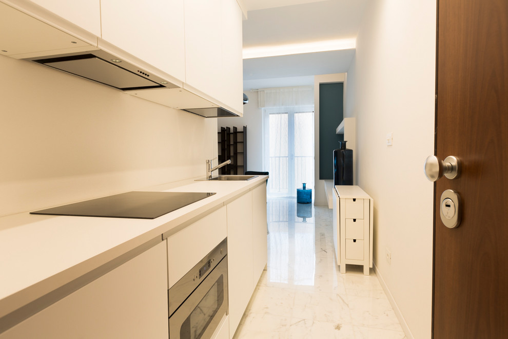 Inredning av ett modernt litet vit linjärt vitt kök med öppen planlösning, med en nedsänkt diskho, släta luckor, vita skåp, rostfria vitvaror, marmorgolv och vitt golv