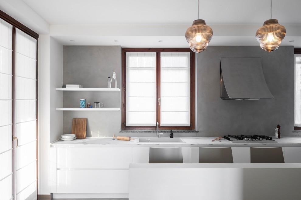 This is an example of a large contemporary l-shaped open plan kitchen in Milan with a built-in sink, flat-panel cabinets, white cabinets, laminate countertops, porcelain flooring, no island, grey floors and white worktops.