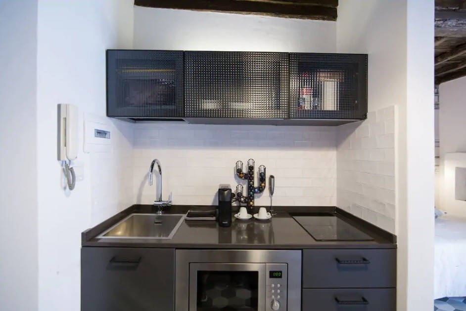 Foto på ett litet industriellt brun linjärt kök med öppen planlösning, med en enkel diskho, luckor med glaspanel, grå skåp, bänkskiva i kvarts, grått stänkskydd, stänkskydd i keramik, rostfria vitvaror, klinkergolv i porslin och grönt golv