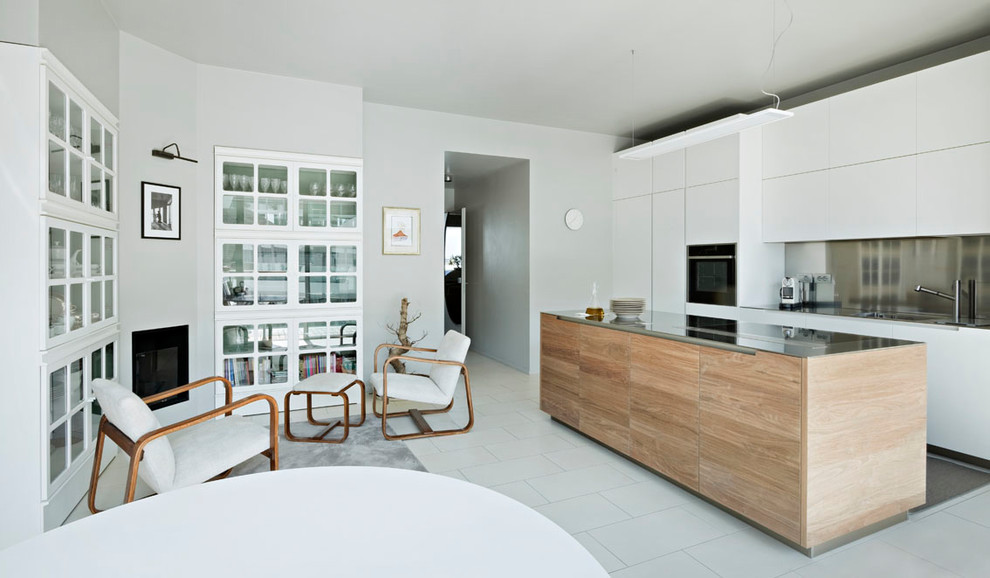 Inspiration for a medium sized contemporary single-wall kitchen/diner in Milan with flat-panel cabinets, white cabinets, stainless steel worktops, metallic splashback, black appliances, an island and white floors.