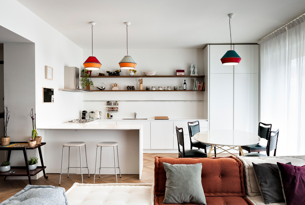 Offene Moderne Küche in U-Form mit flächenbündigen Schrankfronten, weißen Schränken, Küchenrückwand in Weiß, braunem Holzboden, weißer Arbeitsplatte, Unterbauwaschbecken und Halbinsel in Mailand