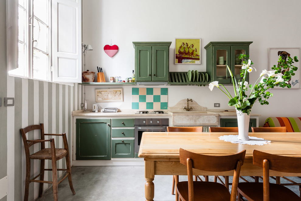 Lantlig inredning av ett beige linjärt beige kök med öppen planlösning, med en rustik diskho, skåp i shakerstil, gröna skåp, rostfria vitvaror, betonggolv och grått golv