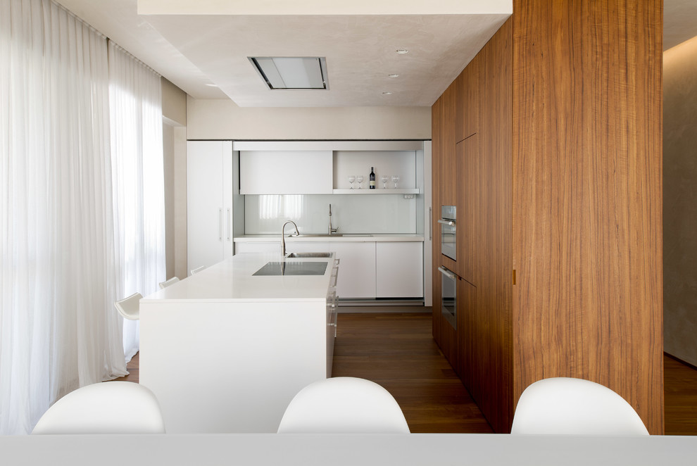ヴェネツィアにあるコンテンポラリースタイルのおしゃれなキッチン (フラットパネル扉のキャビネット、白いキャビネット、白いキッチンパネル、ガラス板のキッチンパネル、シルバーの調理設備、無垢フローリング) の写真