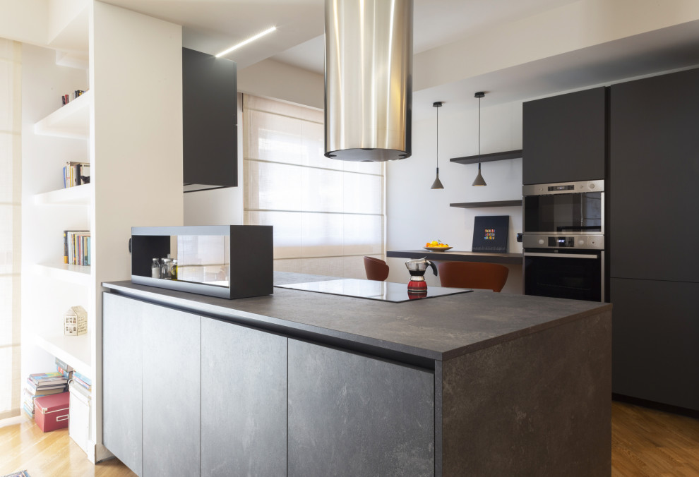 Immagine di una cucina minimal di medie dimensioni con lavello da incasso, ante lisce, ante nere, top in laminato, elettrodomestici in acciaio inossidabile, parquet chiaro e top nero